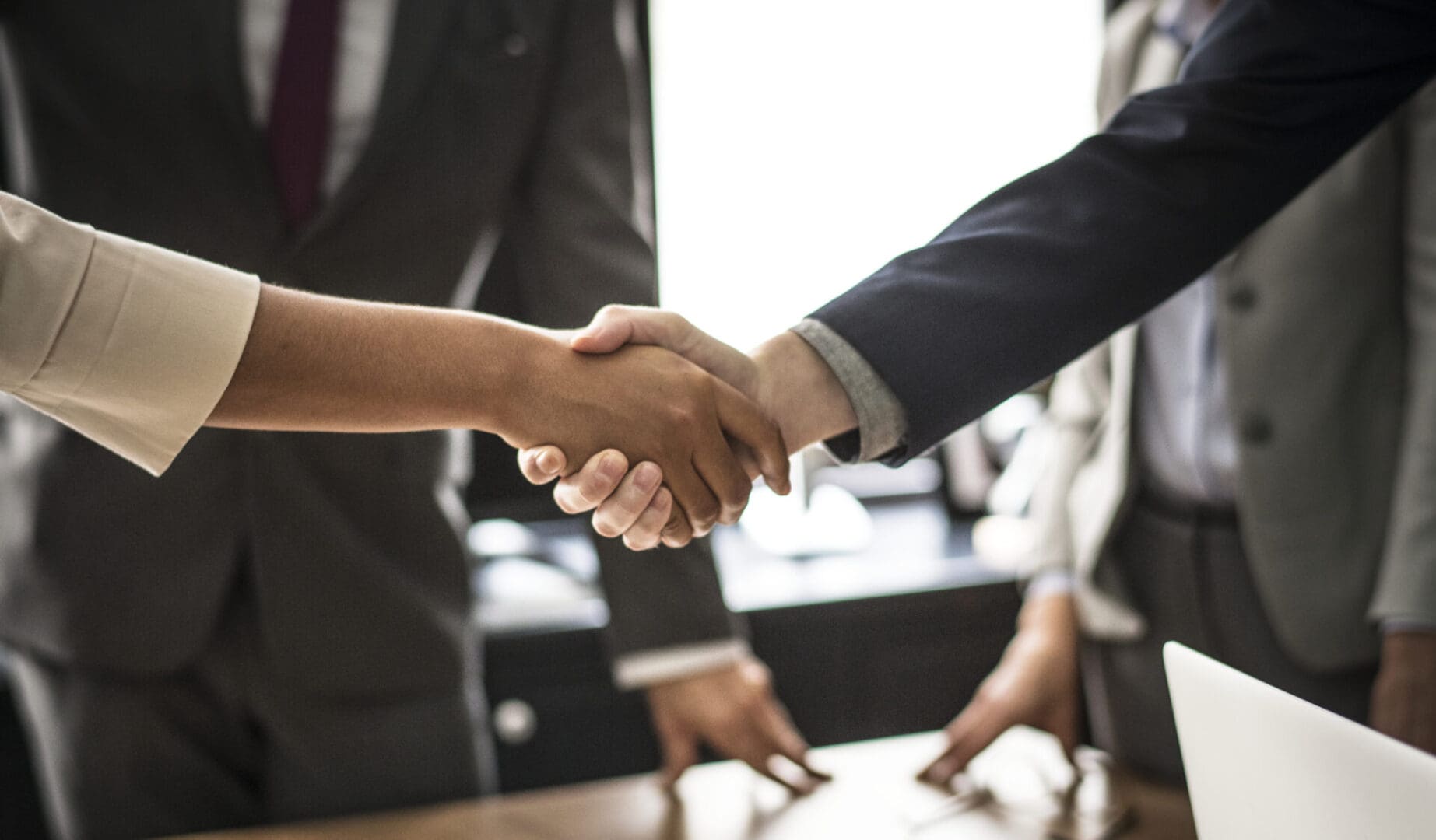 Two people shaking hands over a table.