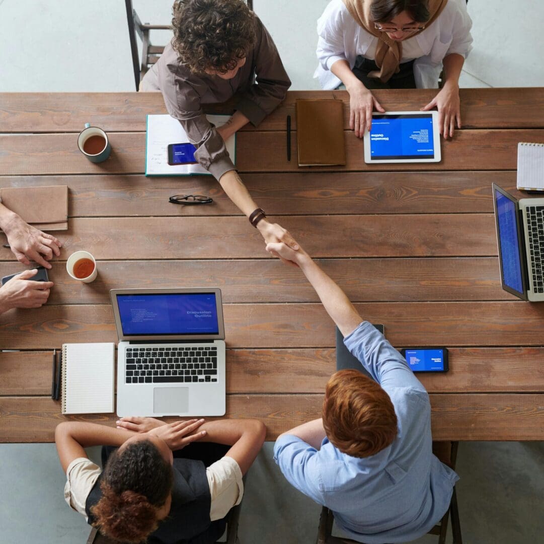 A group of people sitting at a table with laptops.